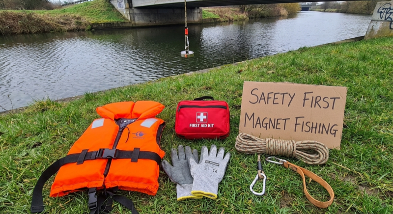 Magnetfischer mit Schutzhandschuhen an einer Brücke